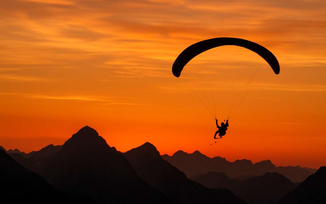 Ride the wind: paraglider silhouette over a painted canyon.